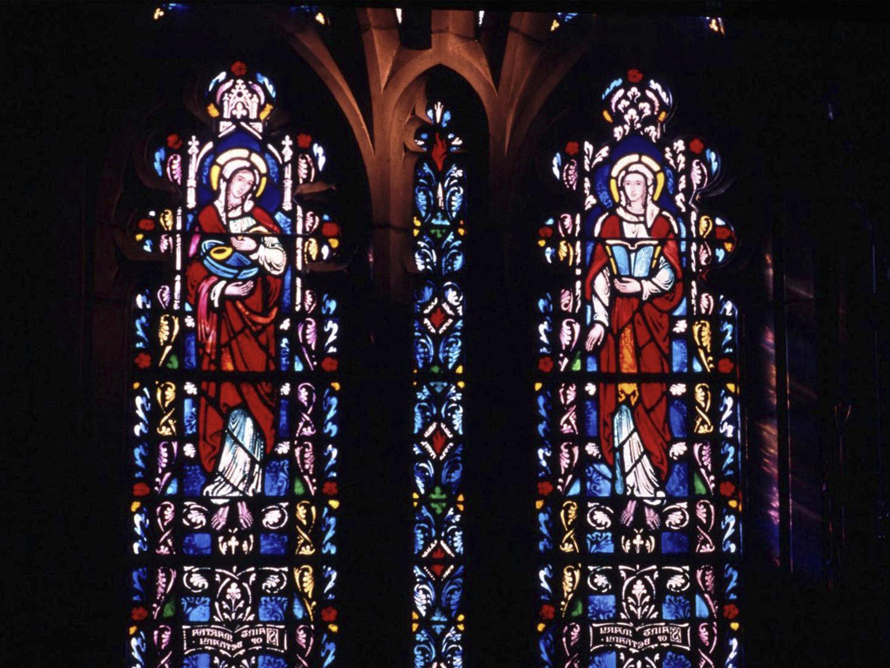两块彩色玻璃面板，分别是抹大拉的玛利亚和玛利亚, 耶稣的母亲被刻在教堂的石墙上