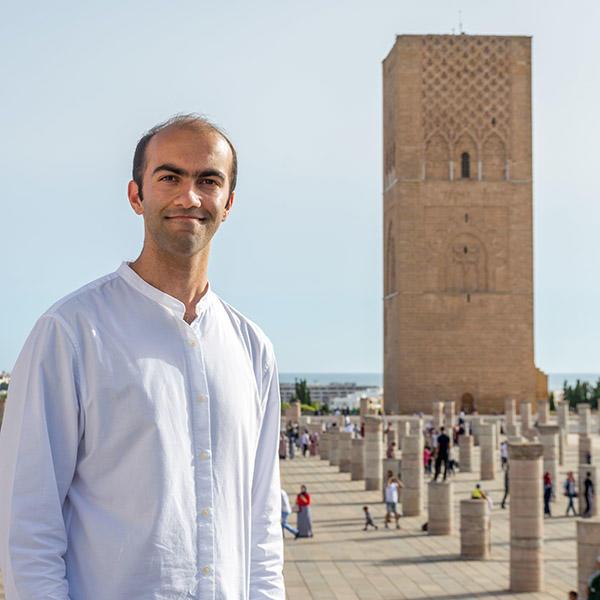 一个年轻人站在一座摩洛哥塔前