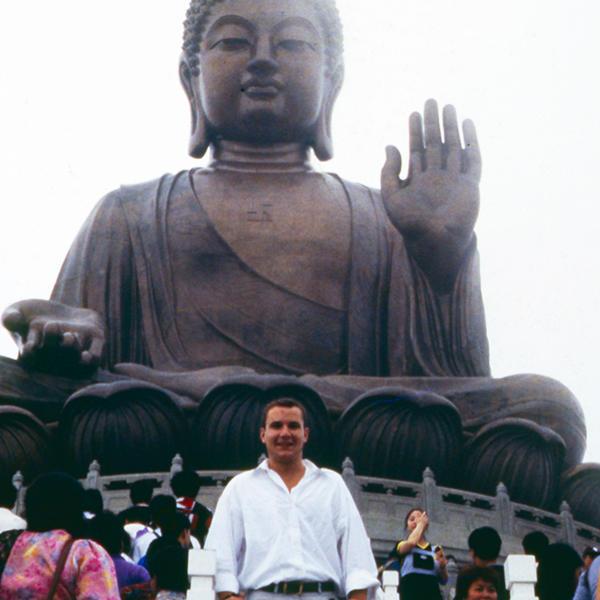 一个年轻人站在一尊巨大的佛像前