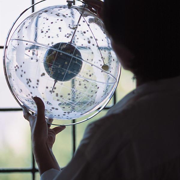 a person holds a model of the earth surrounded by stars on a clear globe